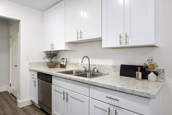 A kitchen with white cabinets and a marble countertop.